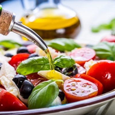 Pouring olive oil into italian caprese salad