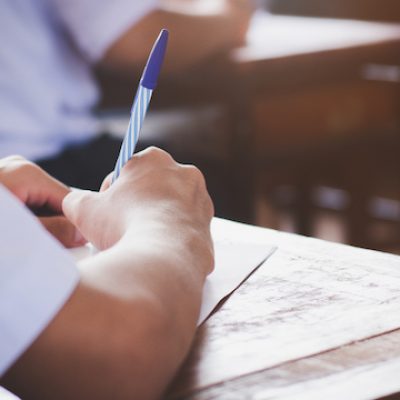 Close up hand of student reading and writing during an exam