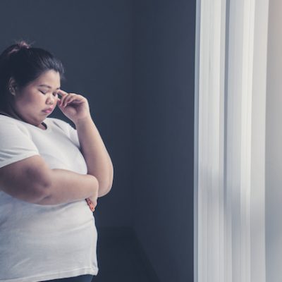 Woman with obesity thinking near the window