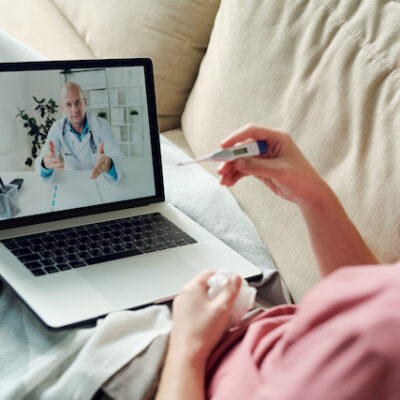 Sick man with laptop speaking with his doctor.
