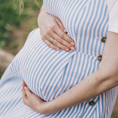 Close-up of pregnant woman in a delicate blue striped dress.