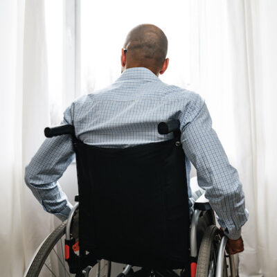 Man in a wheelchair looking out a window.