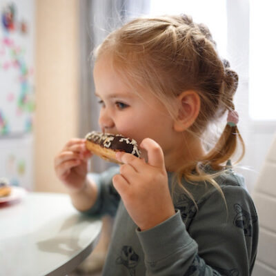 Little girl eating cake while sitting at the kitchen table.