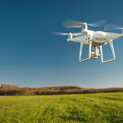 Drone flying over a green field.