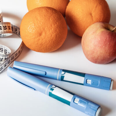 Ozempic pen on a table with a measuring tape and some fruit.
