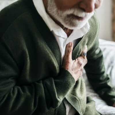 An elderly man holding his heart in pain.