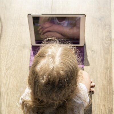 Little girl child lying on the floor looking at a tablet PC.