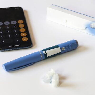 Ozempic Insulin injection pen next to a calculator.