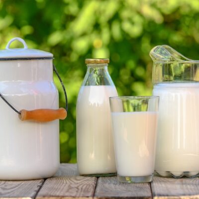 Glass and jug of fresh milk on wooden table.