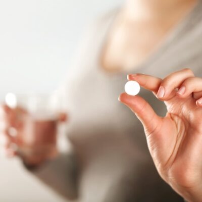 Patient holding a pill and a glass of water.