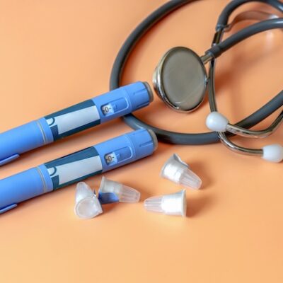 Obesity medications pens and a stethoscope on an orange table.