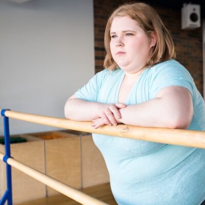 Young woman with obesity standing at a ballerina bar.