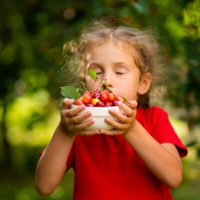 A girl holding bowl of cherries.
