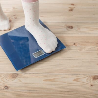 Female feet in socks stepping on a scale.