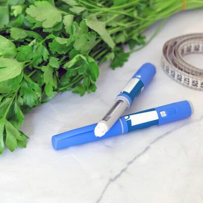 Ozempic pens, a tape measure, and parsley on a table.