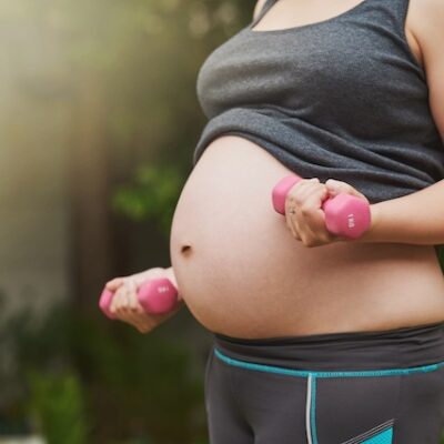 Pregnant woman with obesity using dumbbells.