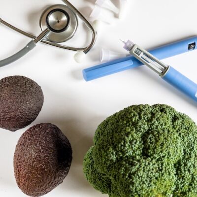 GLP-1 pens on a table with vegetables and a stethoscope.