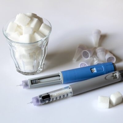 GLP-1 medications and a glass filled with sugar cubes on a table.
