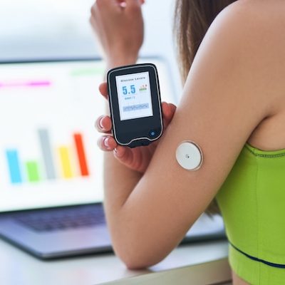 Diabetic patient using remote sensor and laptop for control and online monitoring.