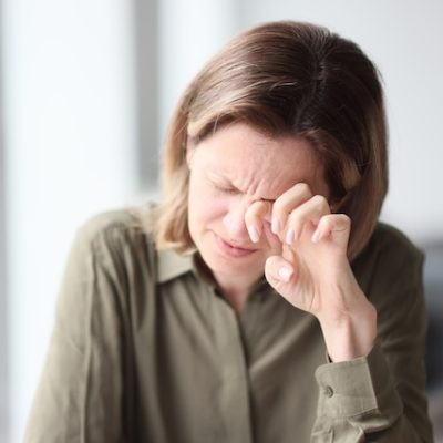 Woman rubbing her eye in pain.
