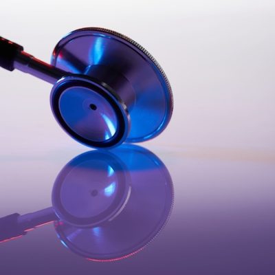 Close up of a stethoscope on a white background with reflection.