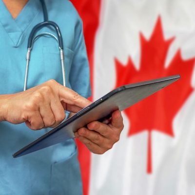 Surgeon or doctor using a digital tablet on the background of the Canada flag.