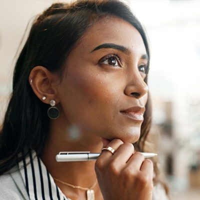 Woman healthcare professional holding a pen and deep in thought.