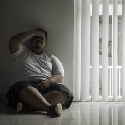 Man sitting on the floor by himself looking lonely.