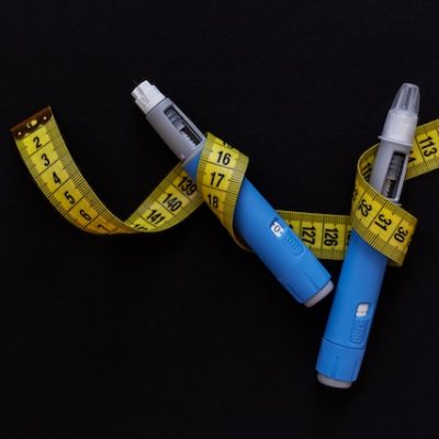 Ozempic pens and measurement tape on a black background.