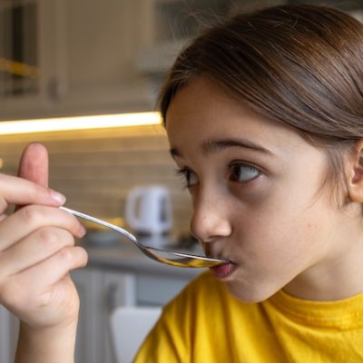 Hungry girl eats yogurt.