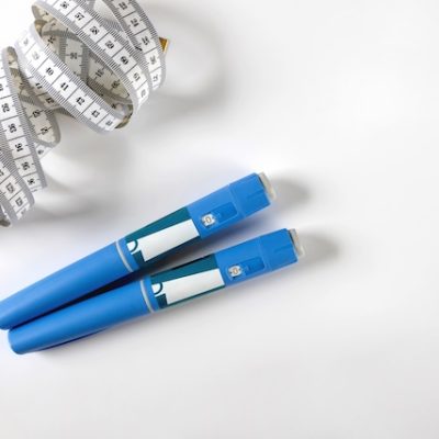 Ozempic pen and a tape measure on a white background.