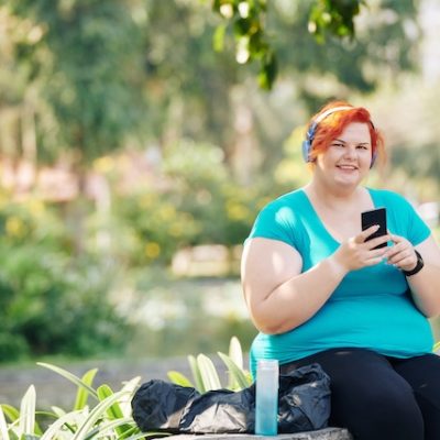 Woman with obesity sitting on a park bench.