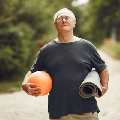 Portrait of happy older man in a park with exercise equipment.