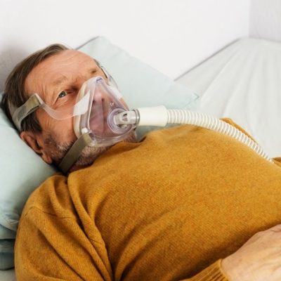 Elderly gentleman having his breathing assisted.