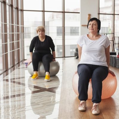 Women using exercise balls in a gym hall.