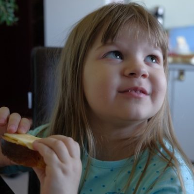 Close up of a little girl holding some food at home.