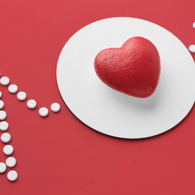 A heart and pills on a red and white background.