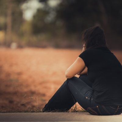 Woman looking sad and sitting alone in a park.
