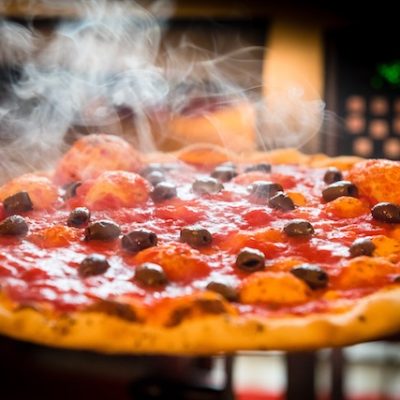 Close up of a pizza steaming after being taken out of the oven.