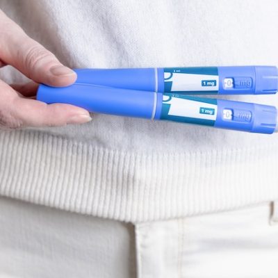 Woman in white clothes holds Ozempic injection pen for diabetics and weight loss.