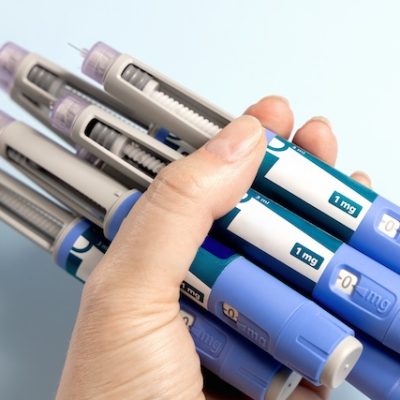 A woman's hand holding many Ozempic pens.