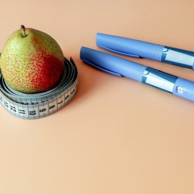 Ozempic insulin injection pens, a pear, and a tape measure.