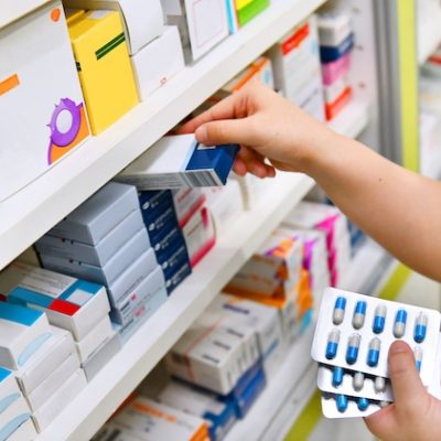 Pharmacist putting medication on a pharmacy shelf.