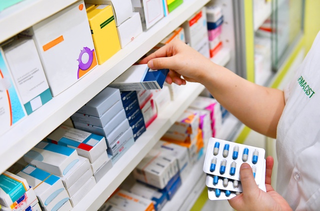 Pharmacist putting medication on a pharmacy shelf.
