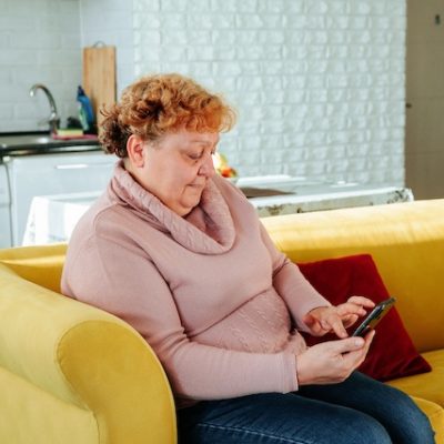 Senior lady using smartphone on the couch.