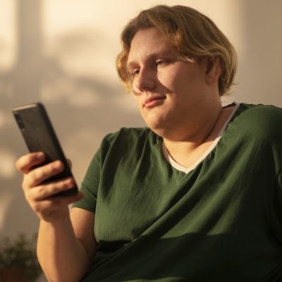 Person with overweight looking at their smartphone.