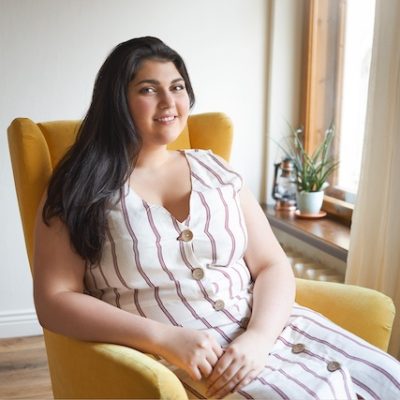 Woman of Indian decent sitting in an armchair.