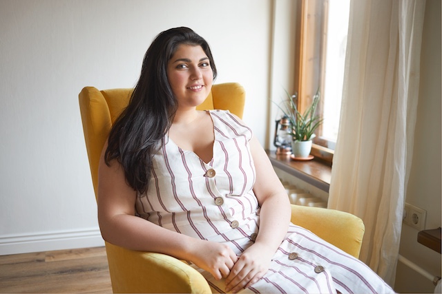 Woman of Indian decent sitting in an armchair.