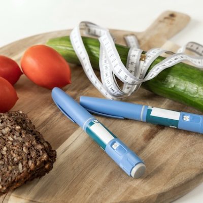 Ozempic pens and vegetables on a chopping board.