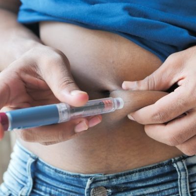 Young man using a GLP-1RA injection pen on abdomen.
